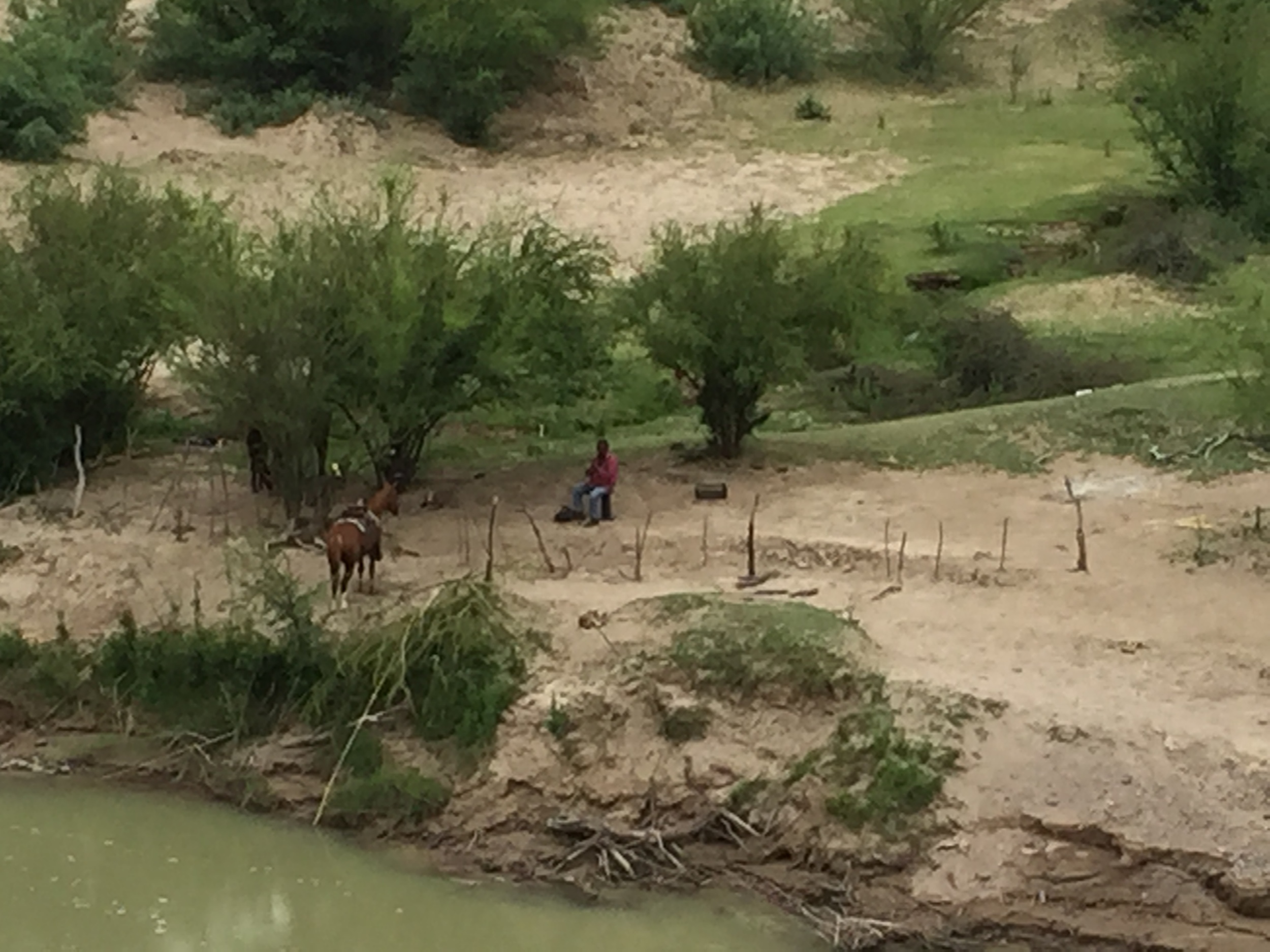 On the Mexican side of the Rio Grande a horseman watches his small group of horses grazing in his corral.&nbsp;